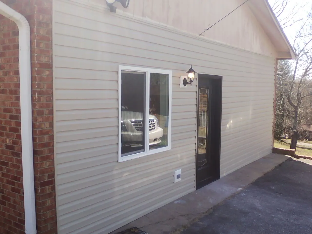 New vinyl siding and entry door on a room addition in Milan