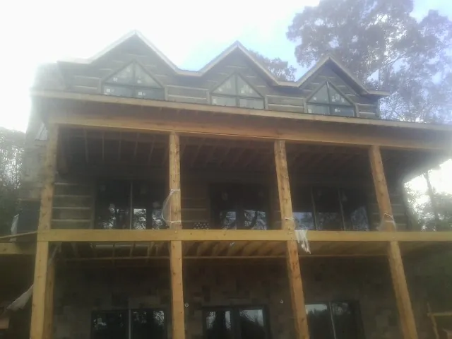 Dormers and porch framing on a large log home under construction — Roof Coating work by our crew in Milan